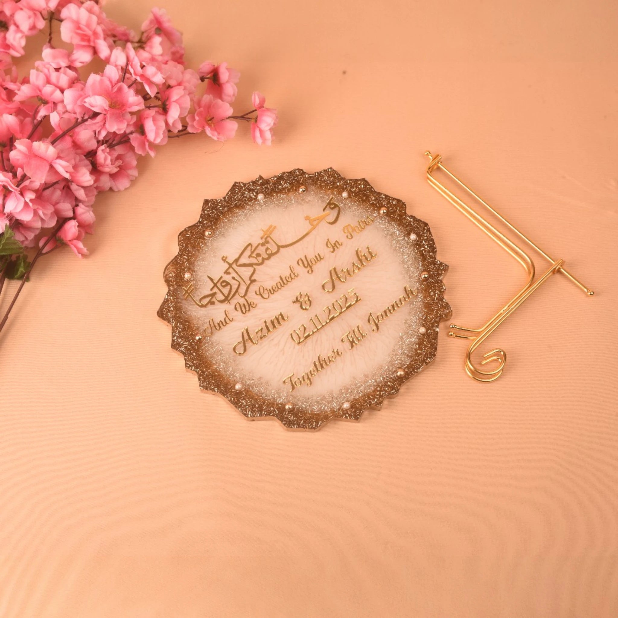 Decorative item with engraved text on a peach background with pink flowers and a gold hairpin.