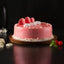 Fudge Cream Cake - Rich Layered Dessert | Chocolate Fudge with pink glaze, white cream swirls, and red macarons on a wooden base.
