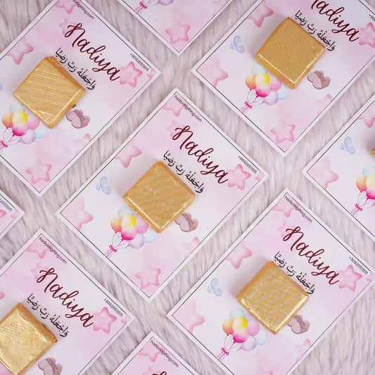 Aqiqah Sweet Blessings Favor featuring gold-wrapped chocolate on pink personalized cards with balloons and stars, ideal for Aqiqah celebrations.