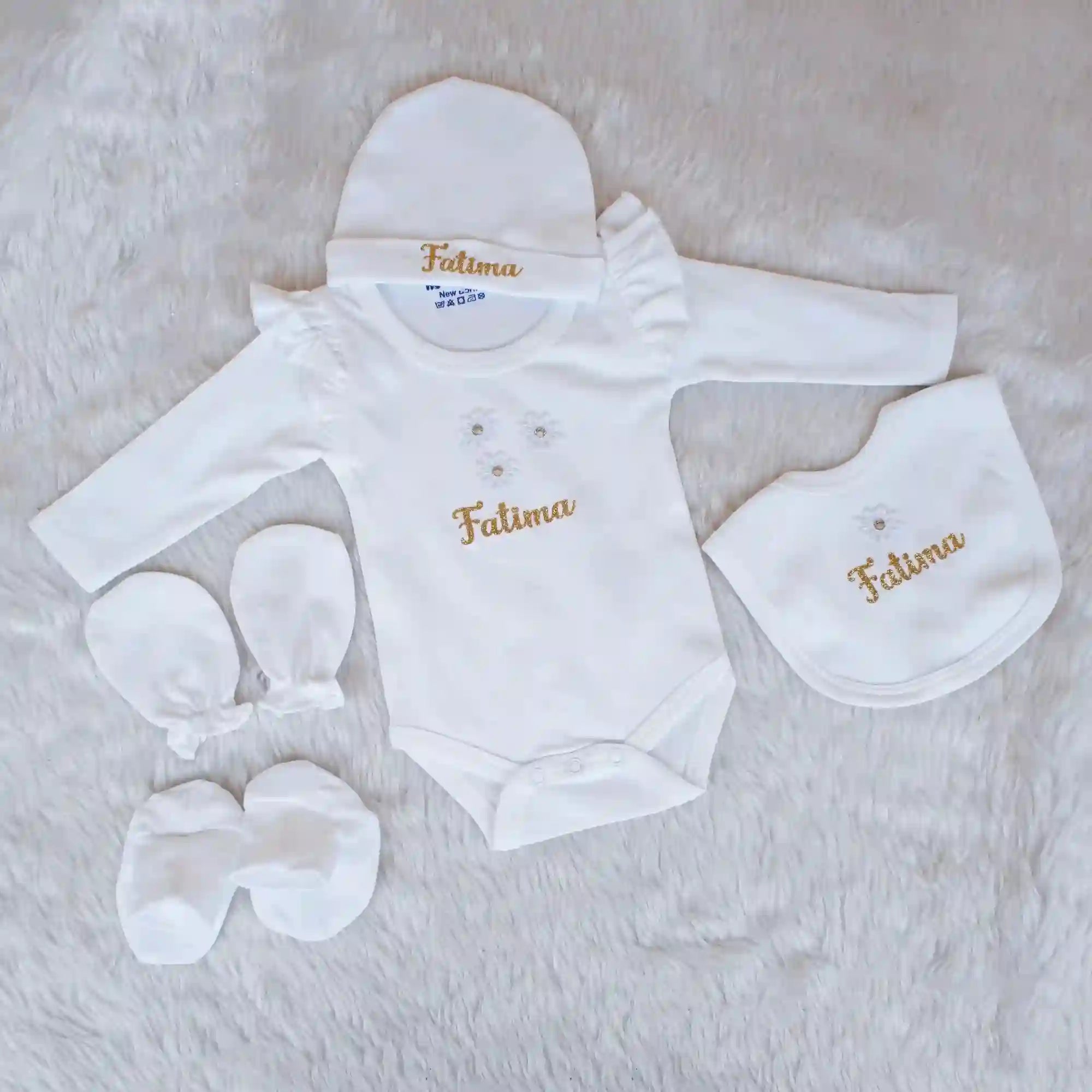 Baby clothing set with 'Fatima' embroidery on a soft surface
