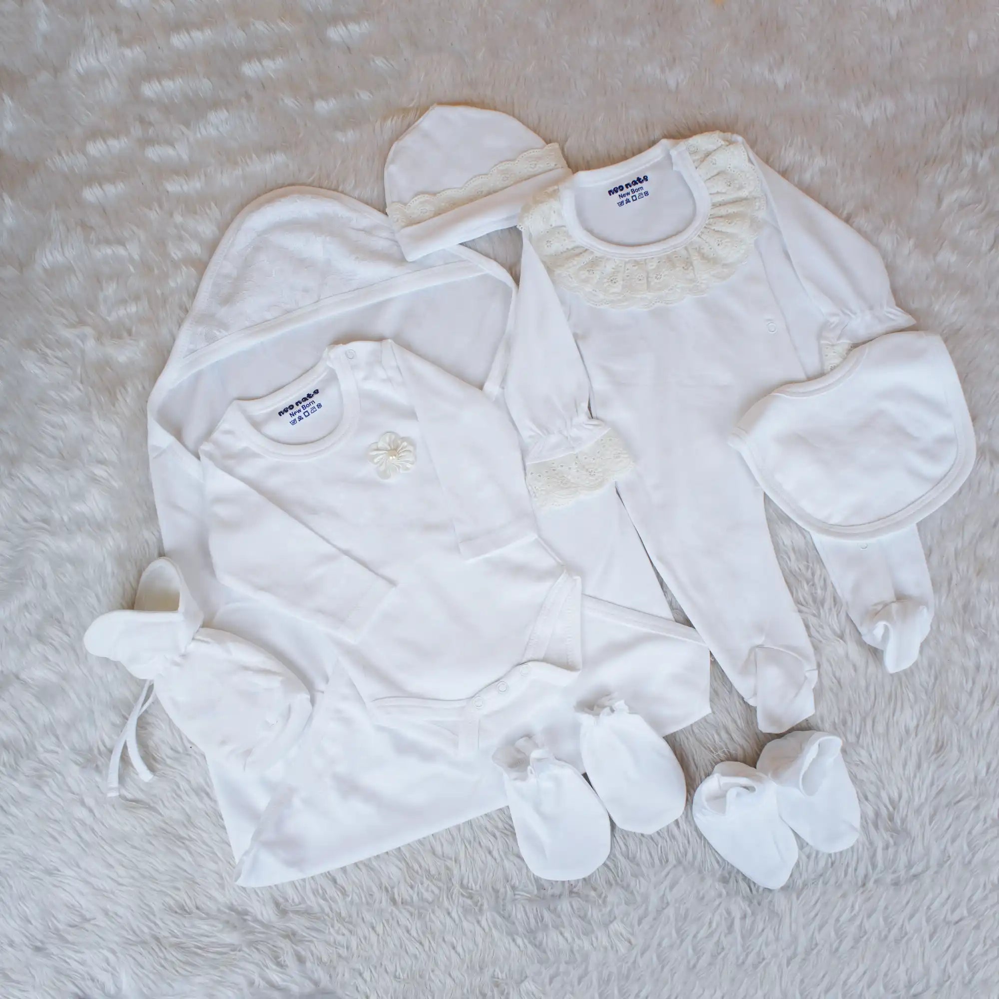 Collection of baby clothes including a onesie, pants, and socks on a textured surface