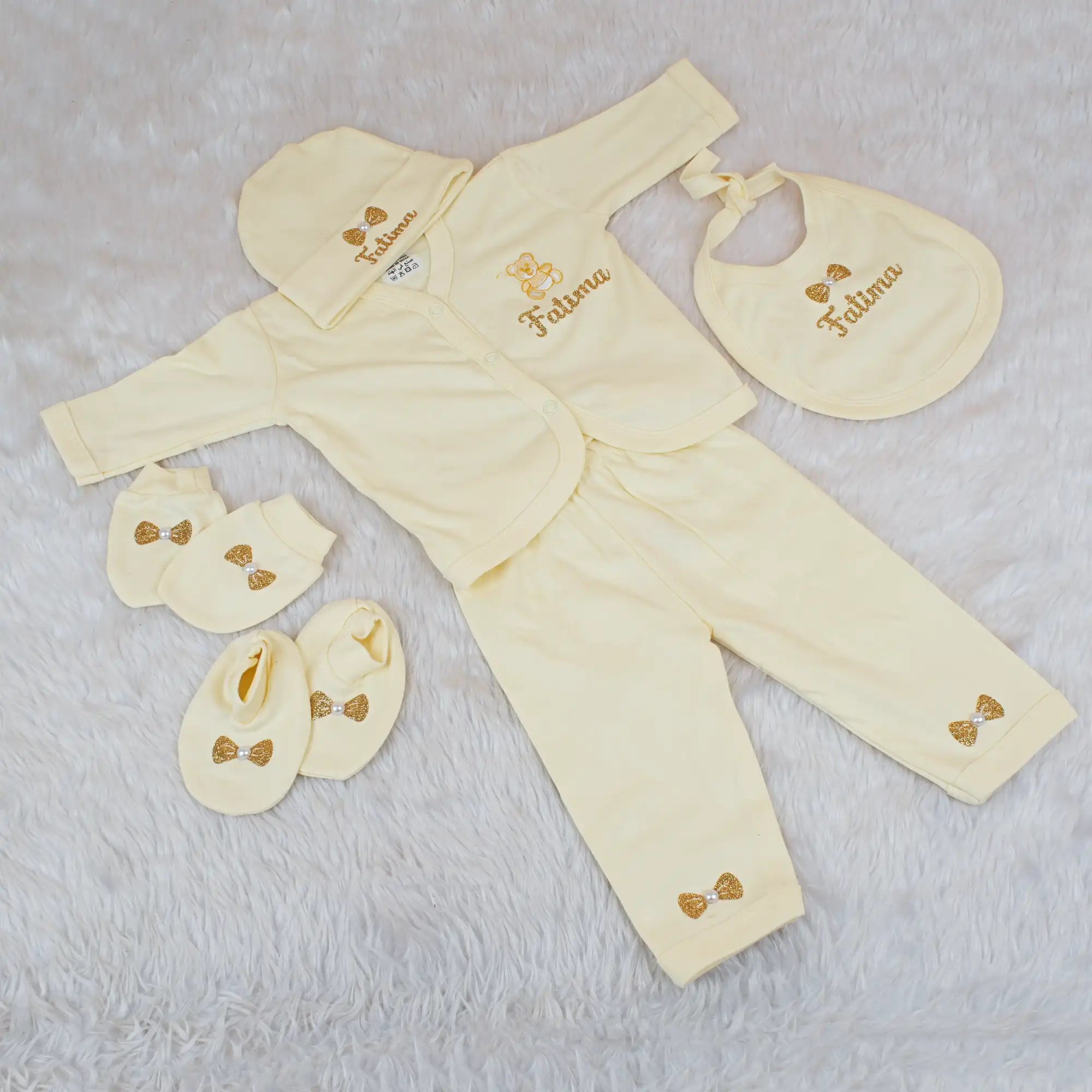 Yellow baby outfit set with matching accessories on a light gray background
