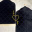 Two black prayer mats with gold embroidery on a marble floor.