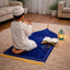 Child praying on blue prayer rug with Quran and lantern