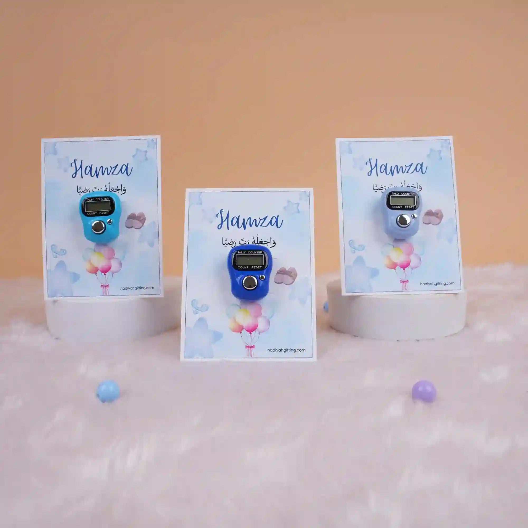 Three Hamza-themed digital Tasbeeh Favors on display stands, elegant Islamic gifts for Aqiqah or religious wedding events.