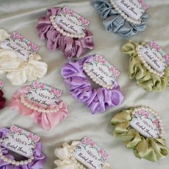 Set of colorful scrunchies with floral labels on a light fabric background