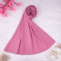 Dark pink studded hijab rolled and displayed on a white surface with floral and pearl accents. Perfect chiffon scarf for elegant modest wear.