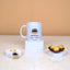 Barakah Blessings Hamper with Hajj Mubarak mug, Kaaba keychain, and chocolates on marble stands. Ideal Hajj souvenir gift set.