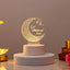 Personalized Eid Mubarak LED lamp emitting a warm glow, featuring an intricate crescent moon design and the name "Saba", displayed on a white cylindrical base.
