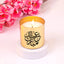 Gold Eid Scented Candle with Arabic calligraphy, lit and styled with pink blossoms. Perfect for Ramadan and Eid home fragrance decor.