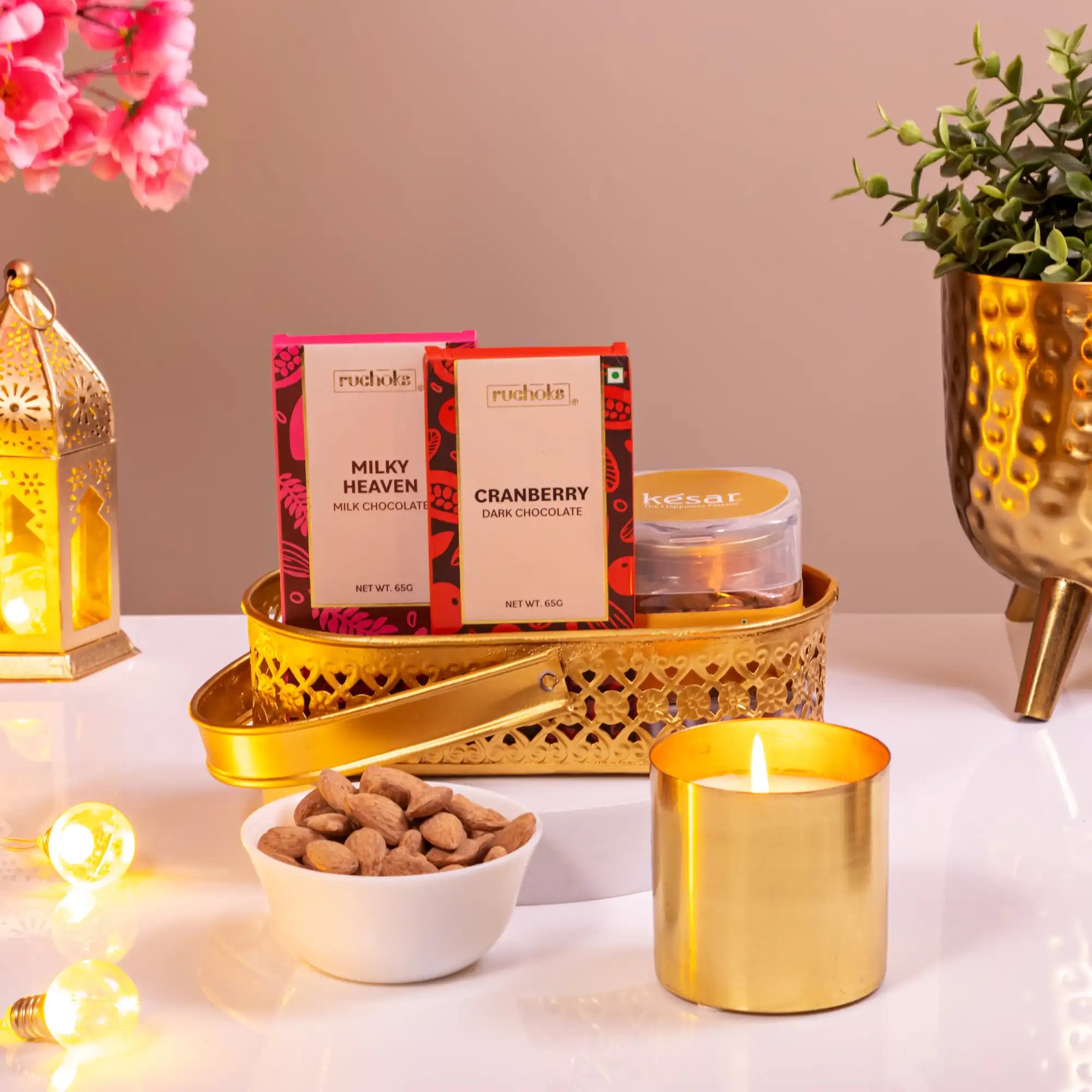 Noor Al-Nazakat Sweet Treats Hamper with chocolates, almonds, kesar sweets, and a lit candle in a golden tray. Perfect for festive and luxury gifting.