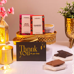 Noor Al-Nazakat Sweet Treats Hamper with premium chocolates, almonds, candle, and thank you card in a golden tray. Ideal sweet gift hamper for celebrations.