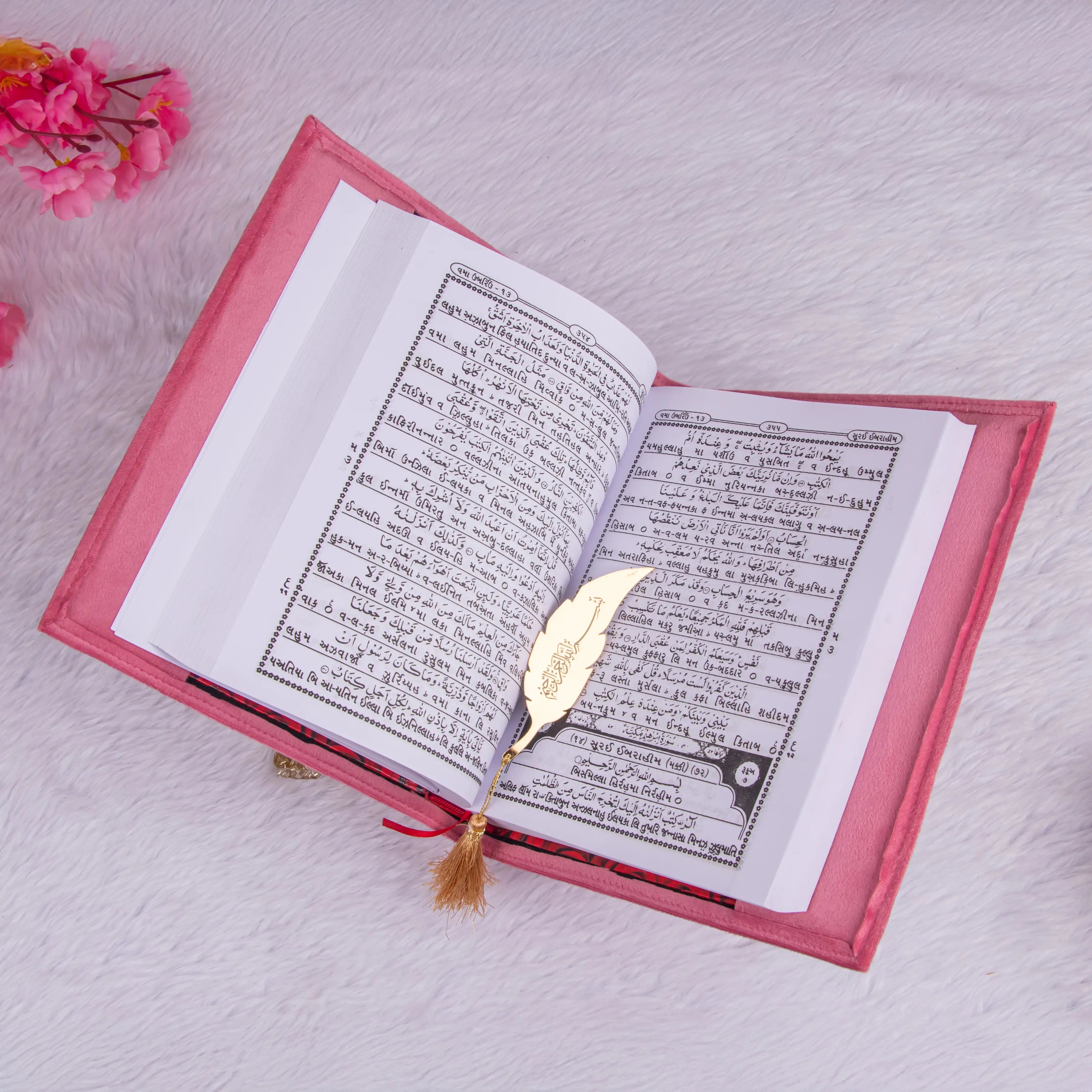 Open pink velvet Quran with Gujarati translation and golden feather bookmark. Included in the Pink Bridal Hamper for diverse gifting.