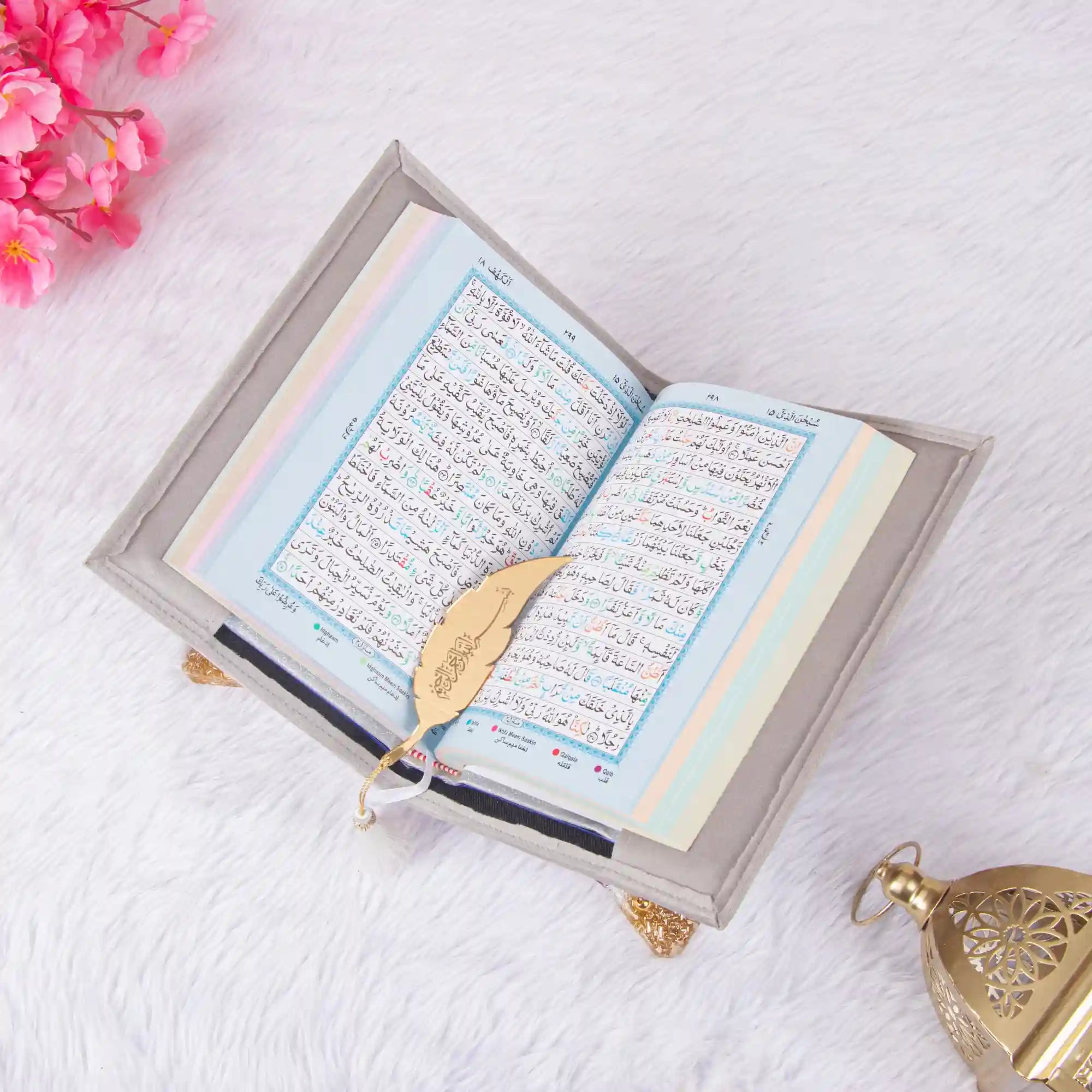 Open Holy Quran with color-coded Tajweed rules and golden feather bookmark from the Velvet Quran Rehal Hamper. Ideal for Quran learning and gifting.