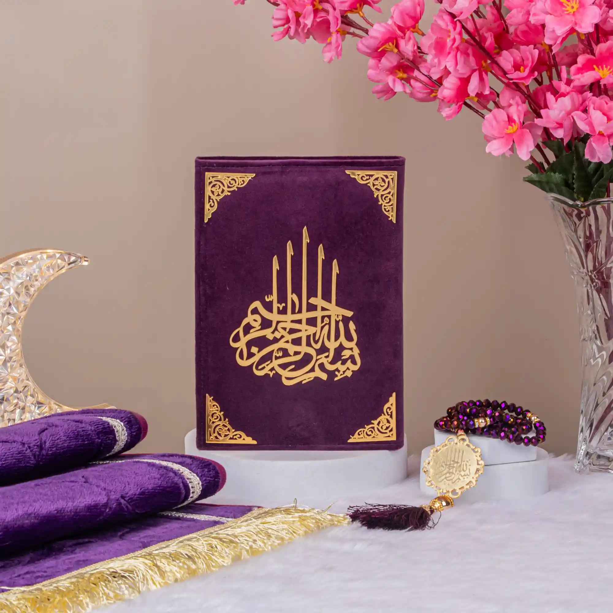 Customised Purple Salah Combo Hamper with premium velvet Quran, prayer mat, and tasbeeh displayed near pink blossoms and crescent decor.