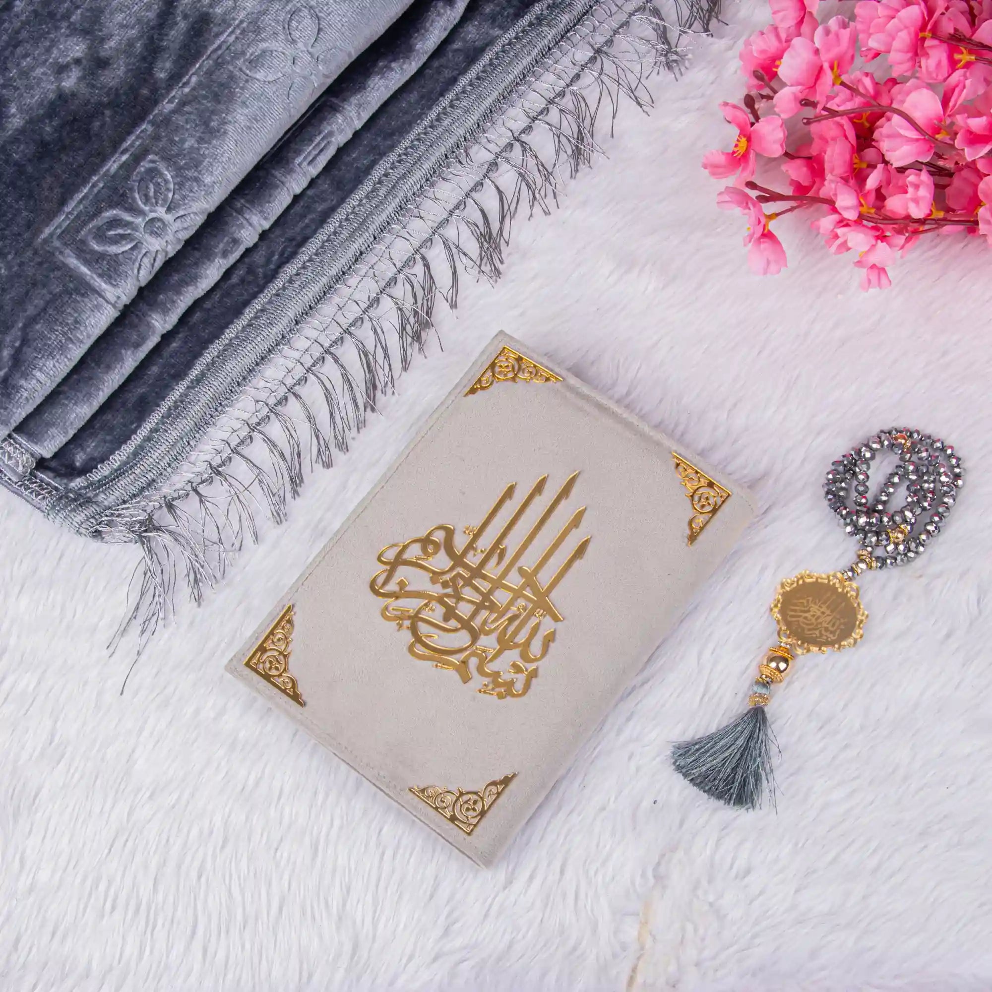 Customised Grey Salah Combo Hamper featuring a velvet Quran, grey Janamaz, and crystal Tasbeeh on a white fur background with pink flowers.