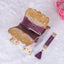Decorative purple and gold item with tassel on a white background