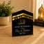 Hajj Mubarak plaque with gold and white text on a wooden surface with decor items.
