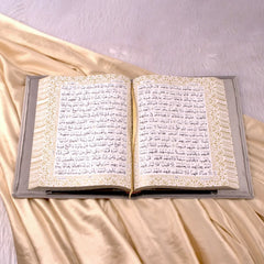 Open Holy Quran with ornate golden border and grey velvet cover from the Velvet Quran Rehal Hamper. Luxurious Islamic gift for special occasions.