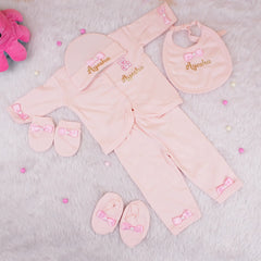 Pink baby outfit set with matching accessories on a light gray background