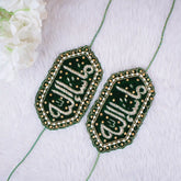 Two green embroidered patches with gold detailing on a white fabric background.