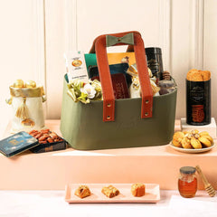Green gift basket with brown handles on a table with various items around