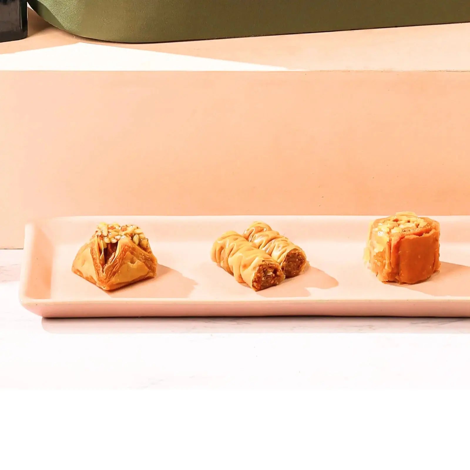 Three pastries on a rectangular plate with a soft pink background