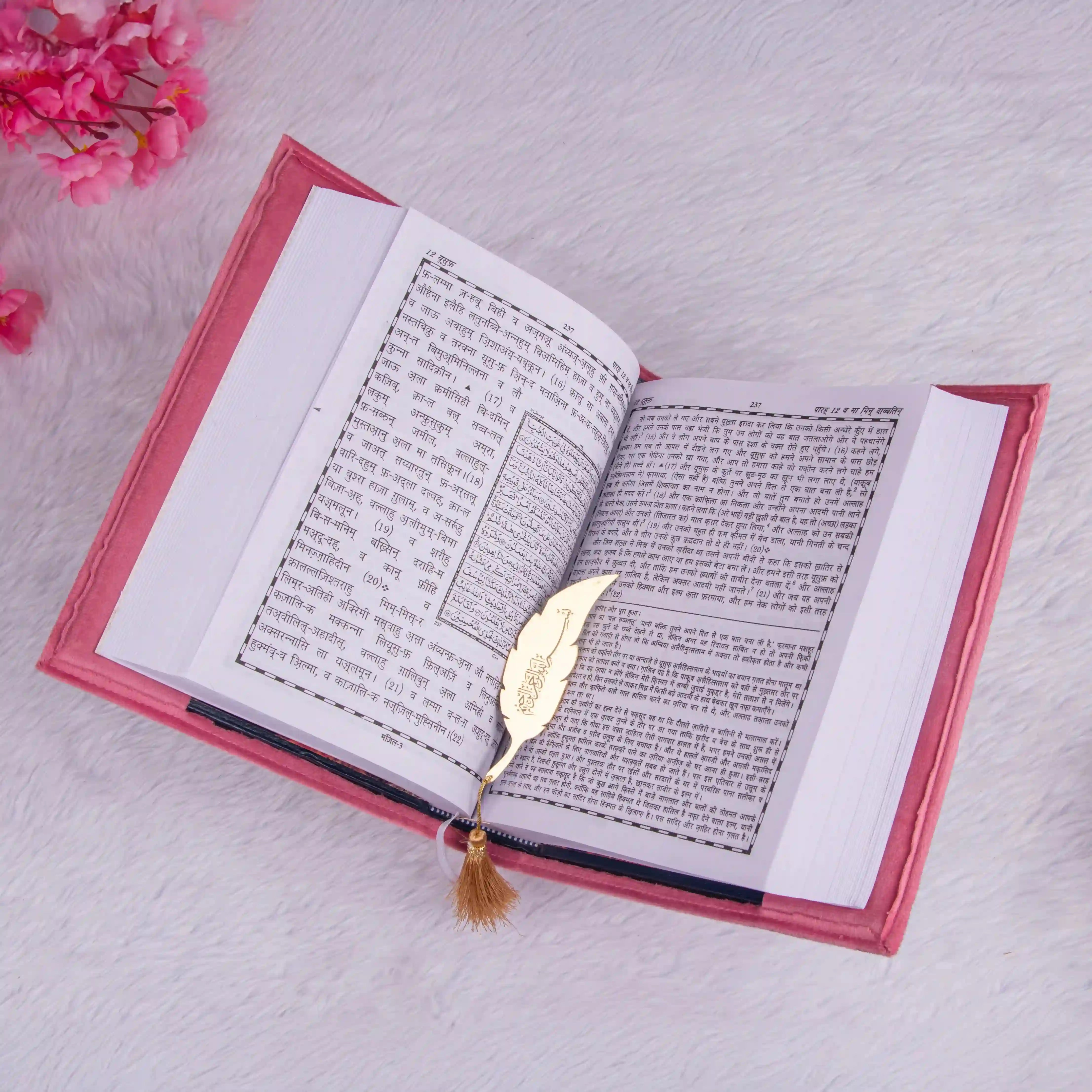 Open pink Premium Velvet Quran with Hindi Translation and golden feather bookmark, showcasing dual-language text for prayer essentials.