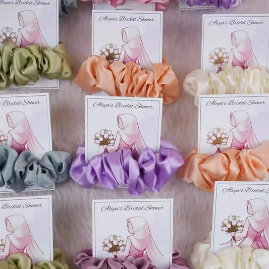 Assorted satin scrunchie card favors for bridal shower with custom illustration and text, ideal wedding ceremony supplies and gifts.