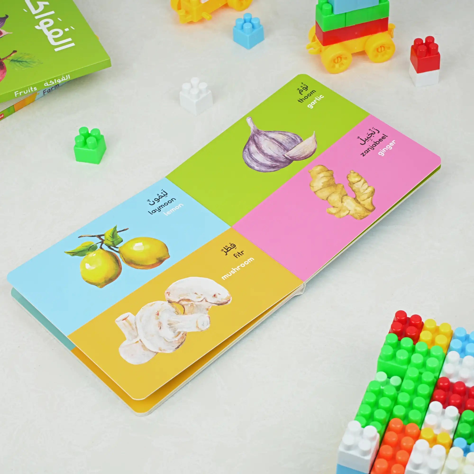 Colorful educational book with vegetable illustrations on a white surface with building blocks.