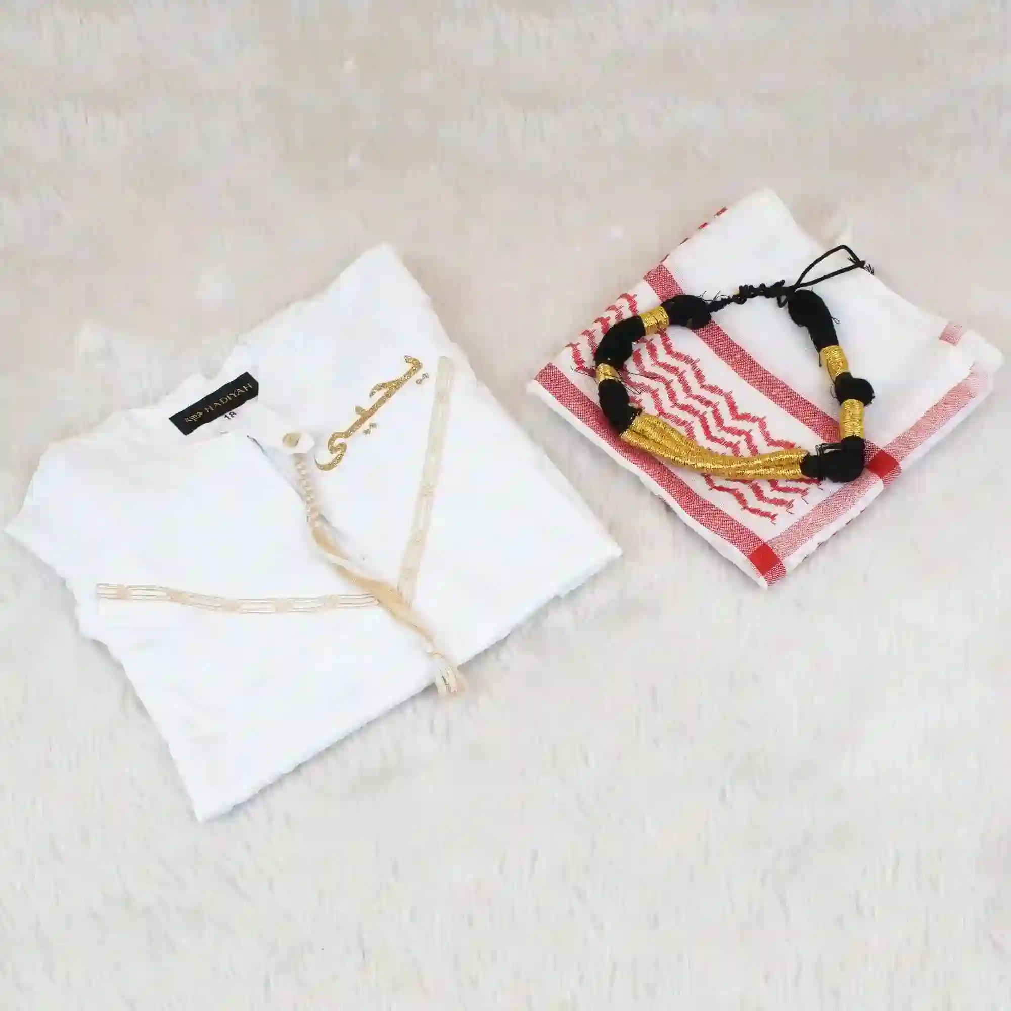 White garment with embroidery and a folded towel with a decorative pattern on a light surface