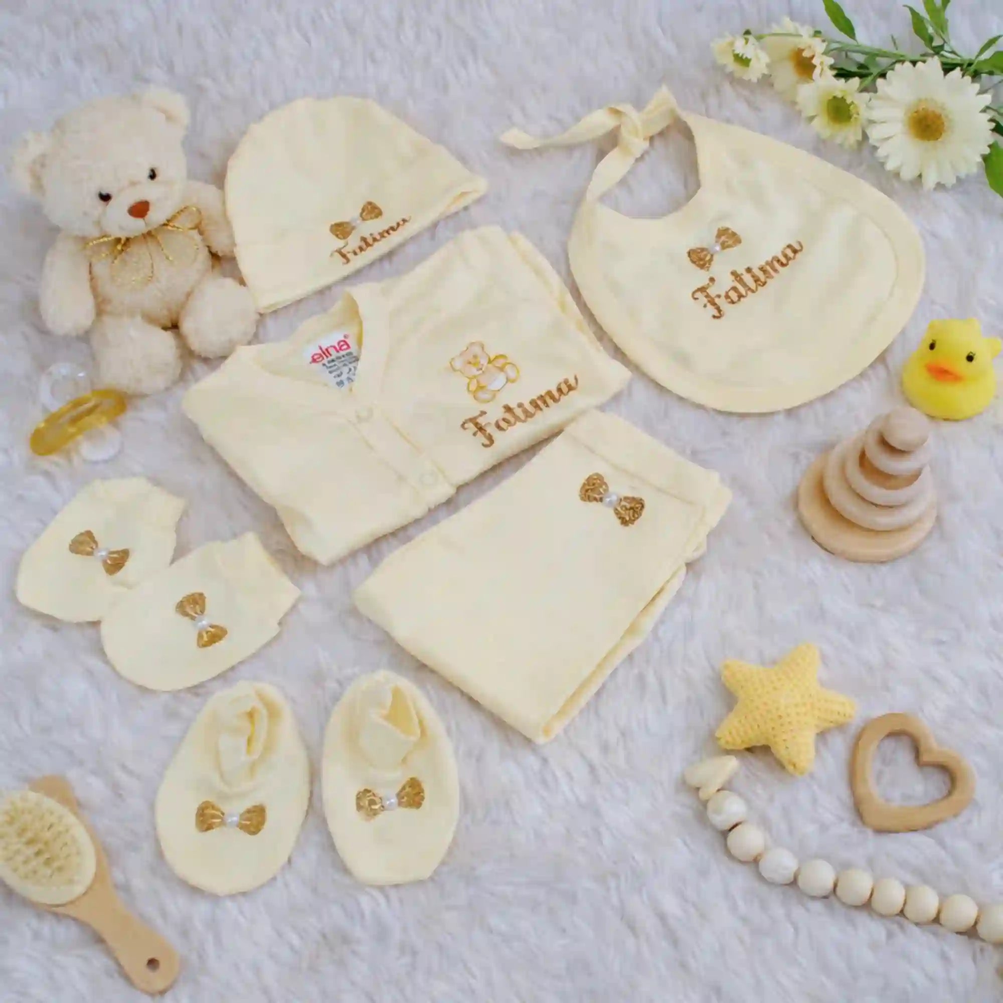 Personalized kids pyjama set with name 'Fatima' in soft yellow, includes cap, mittens, bib, and booties, perfect for newborn gift sets.