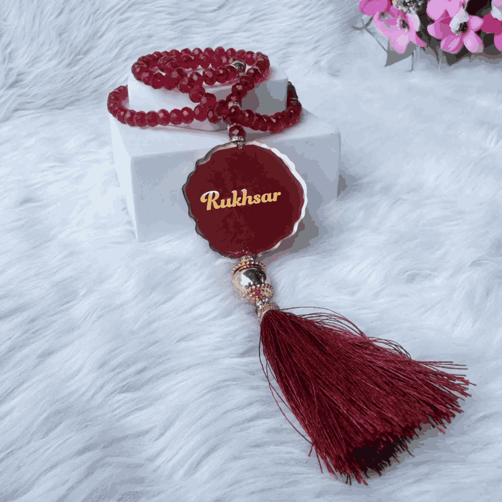 Personalized red tasbeeh with golden name tag and tassel, featured in Amaanat-e-Nikaah Maroon Bling Collection for bridal gifts.