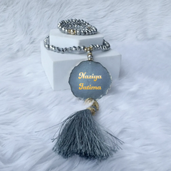 Grey Sequence Sawab-E-Jariya Hamper - Premium Quran Gift Set Online featuring personalized crystal Tasbeeh with name tag and grey tassel on white fur.
