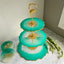 Three-tiered turquoise serving tray with gold accents on a marble surface.