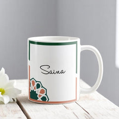 Personalized Umrah Mubarak Floral Mug with custom name 'Saina' and elegant Islamic pattern, perfect for Hajj & Umrah gift hampers.