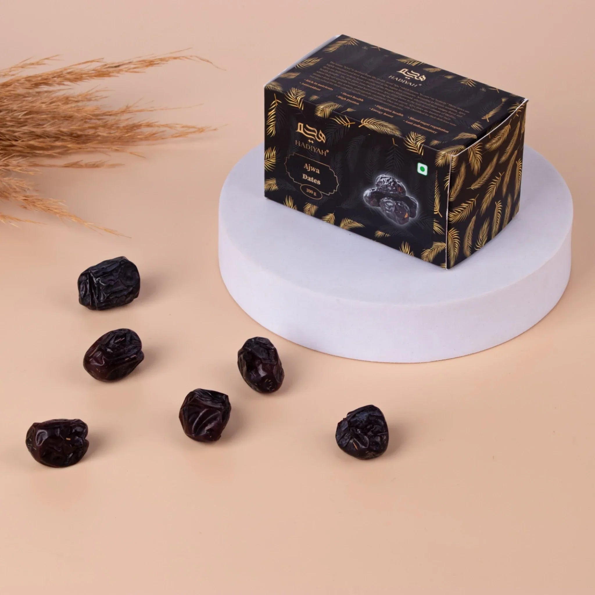 Premium Ajwa dates box with scattered dates on beige background.