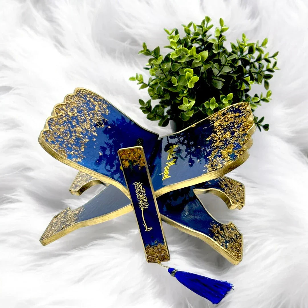 Elegant blue and gold Quran stand with matching bookmark and green plant.