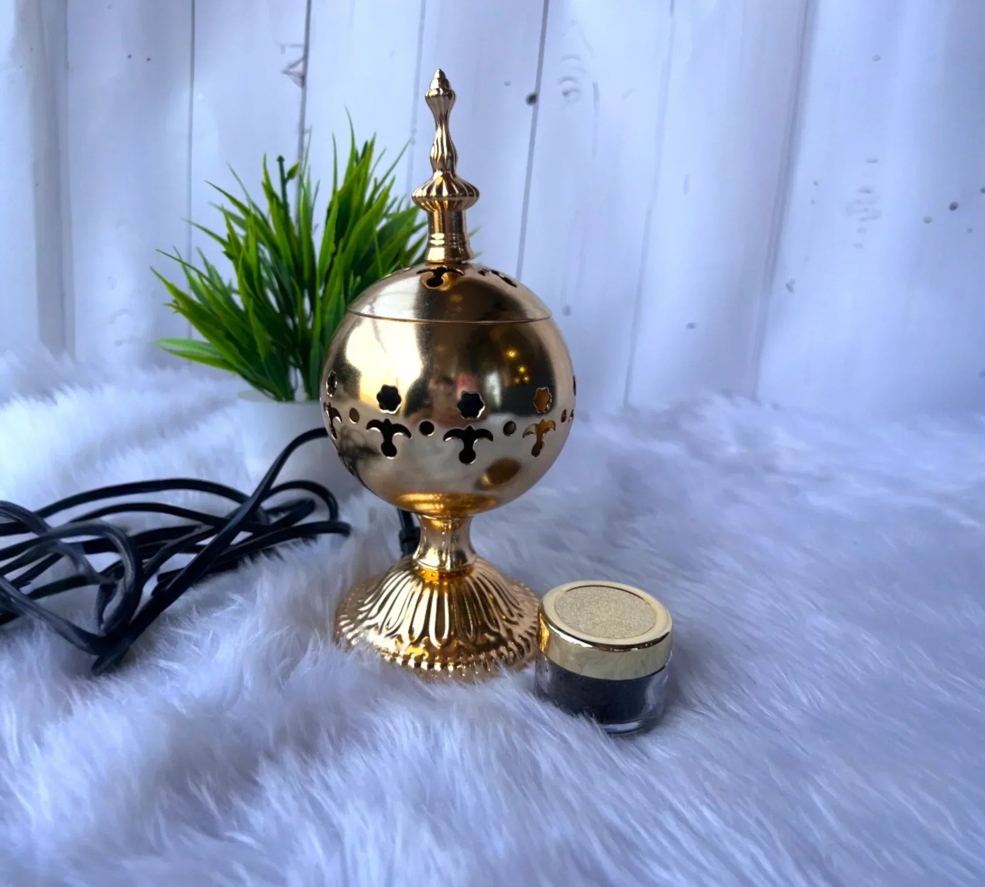 Elegant golden bakhoor burner with rich bakhoor jar on soft fur background