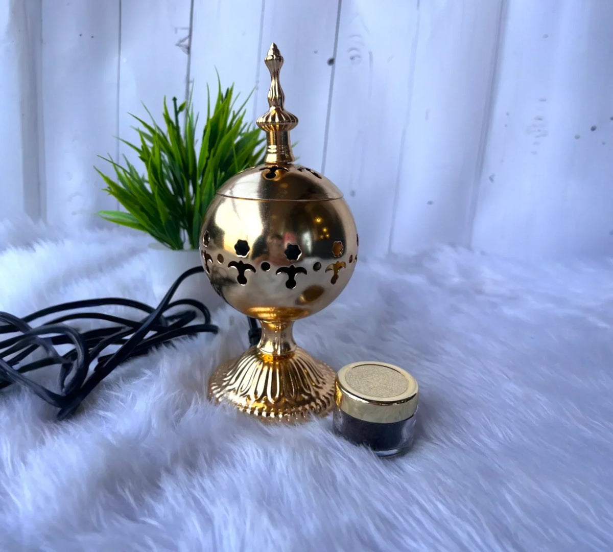 Elegant golden bakhoor burner with rich bakhoor jar on soft fur background