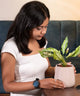 Woman holding rust-free cream self-watering pot, emphasizing durability and suitability for Aglaonema Snow White Plant care.