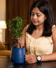 Woman holding a blue pot with a small plant indoors
