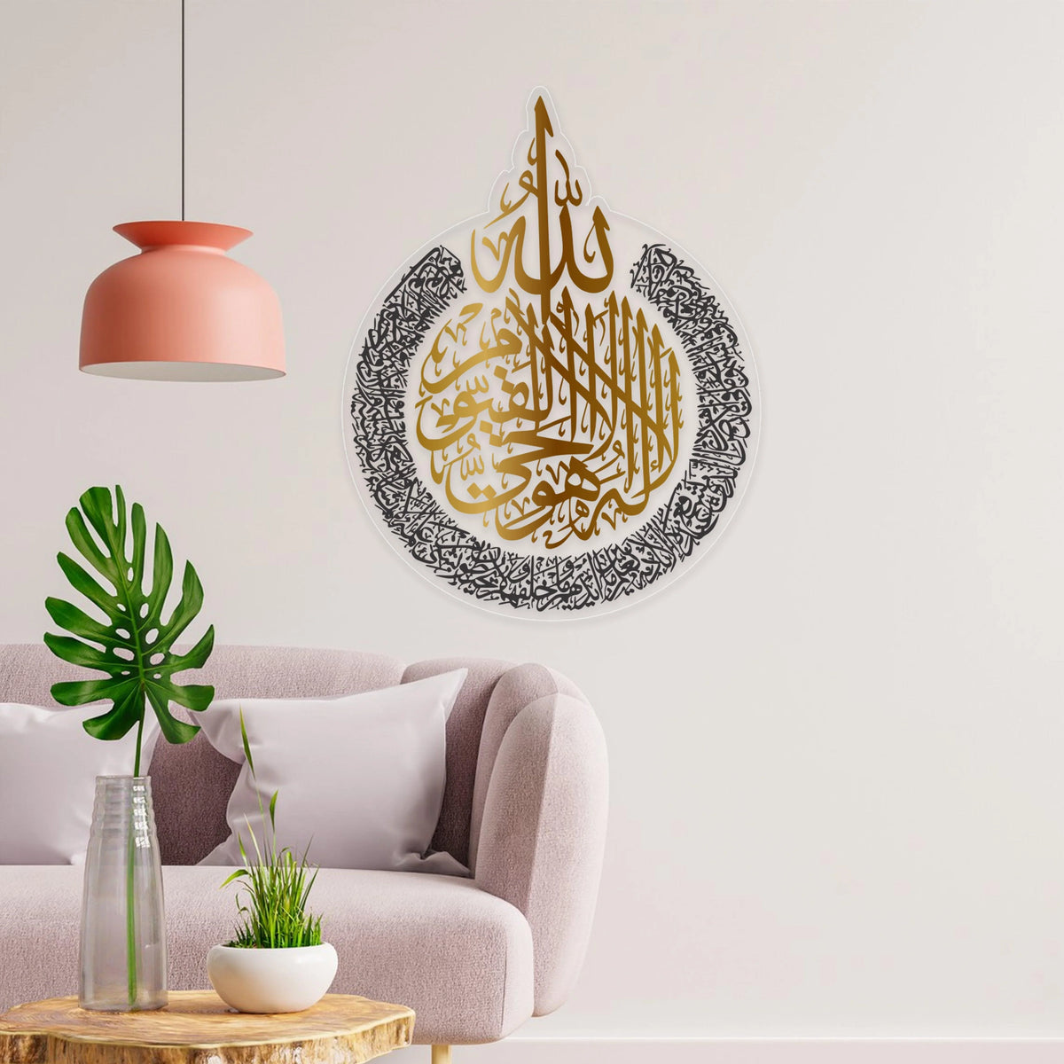 Ayatul Kursi Wall Art in gold and black Arabic calligraphy mounted on a white wall above a modern sofa. Elegant Islamic decor for home or office.
