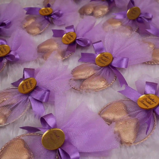 Heart Shower Favors with gold-wrapped chocolate hearts in purple mesh pouches, tied with bows and personalized gold tags for bridal showers.
