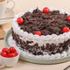 Round Black Forest Cake topped with cherries and chocolate flakes, perfect for celebrations. Order online for same day delivery.