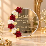 Round gold nikah mirror with pearl edging, red and white roses and personalized wedding names.
