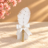 Elegant golden pearl-beaded pen with a white feather and satin bow, styled for wedding gifting.