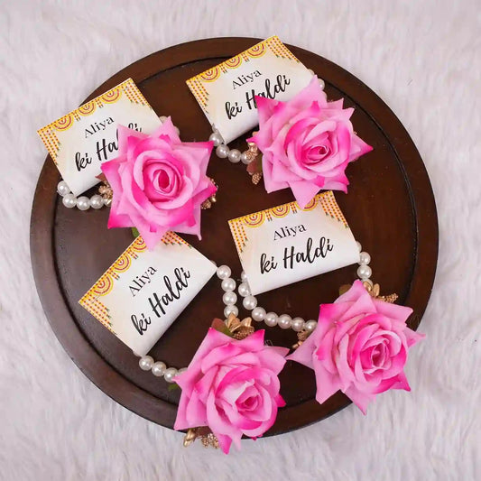 Haldi e Haya Floral Favors featuring pink floral hand bracelets with pearl bands and custom 'Aliya ki Haldi' cards, ideal for wedding celebrations.