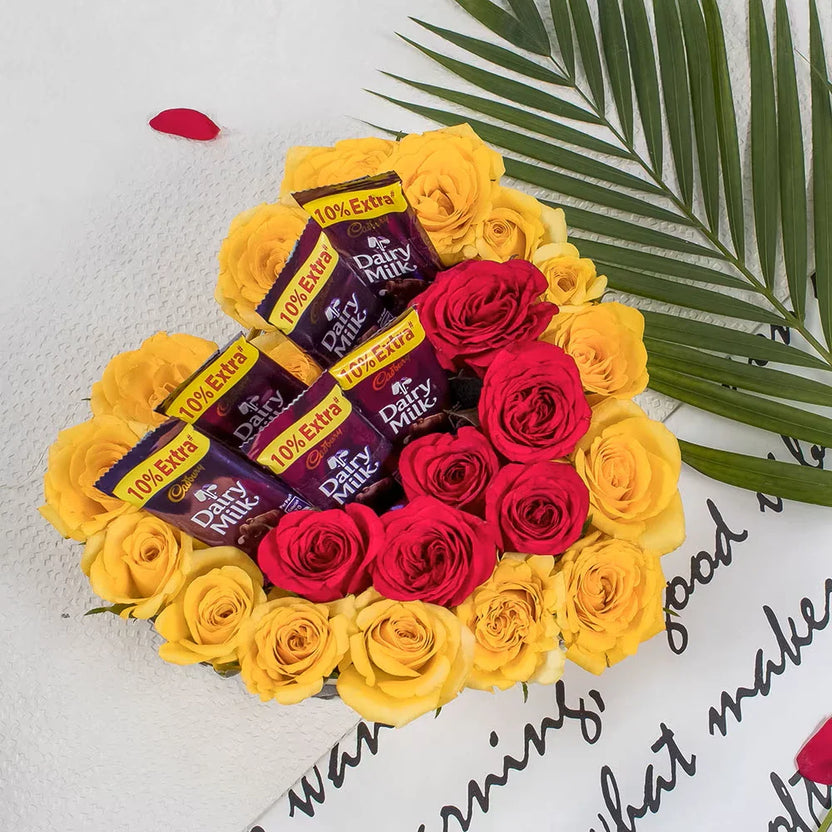 Cadbury With Rose - Chocolate Gift Set featuring Dairy Milk bars arranged with red and yellow roses in a heart-shaped floral bouquet. Ideal for romantic gifts. Main image