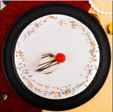 Top view of Vanilla Cake - Moist Delight featuring smooth whipped cream frosting, colorful sprinkles, and cherry garnish, perfect for celebrations.